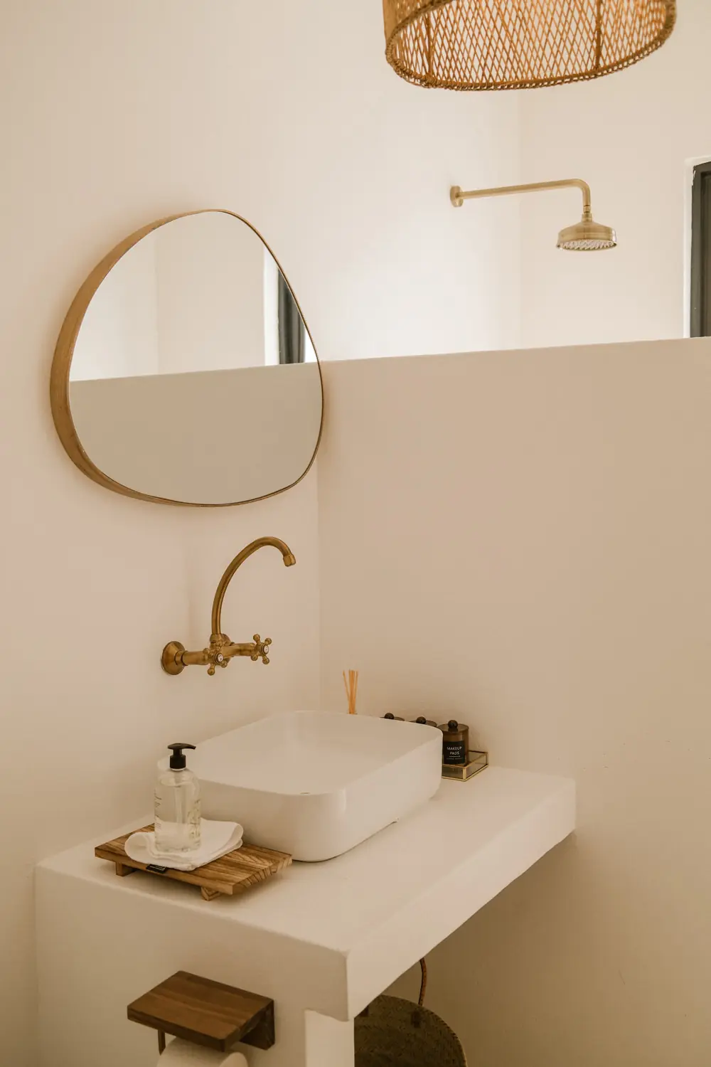 A bathroom with a rounded mirror, a brass tap and a rain shower