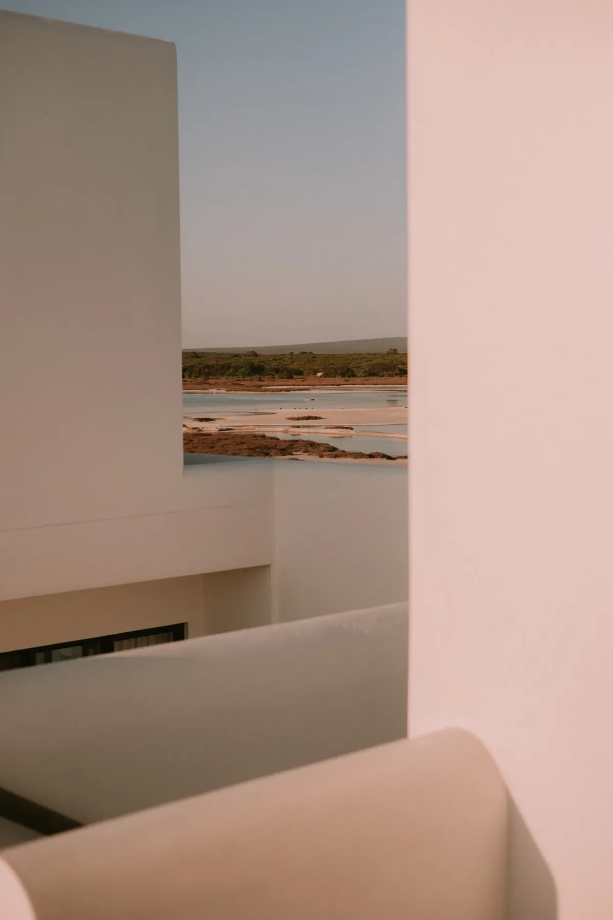 Looking between timber posts and over a whitewashed parapet to the rooftops and water beyond