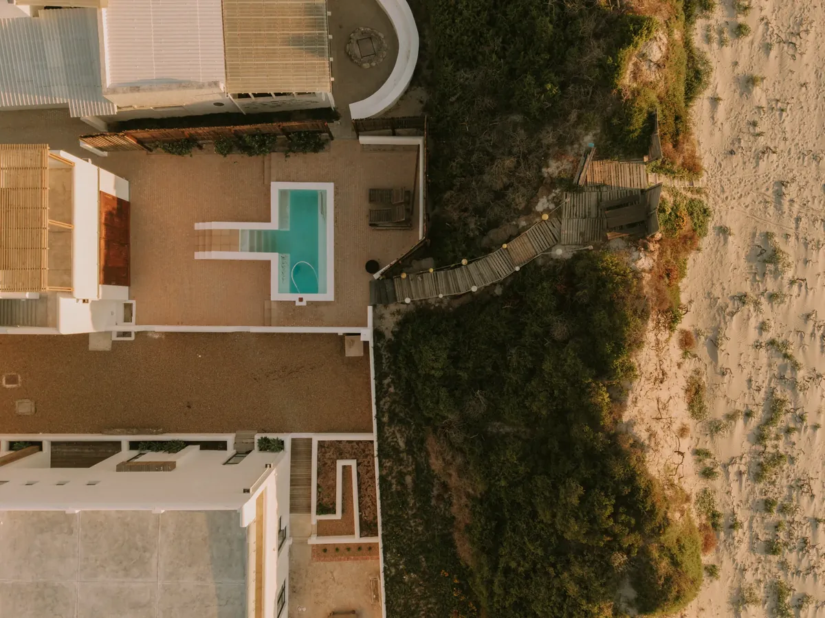 An aerial view of the villa, pool courtyard and boardwalk leading to the beach
