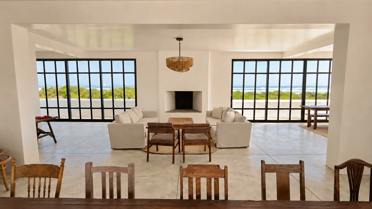 The lounge, with sofas around a fireplace and tall steel-framed windows onto the ocean